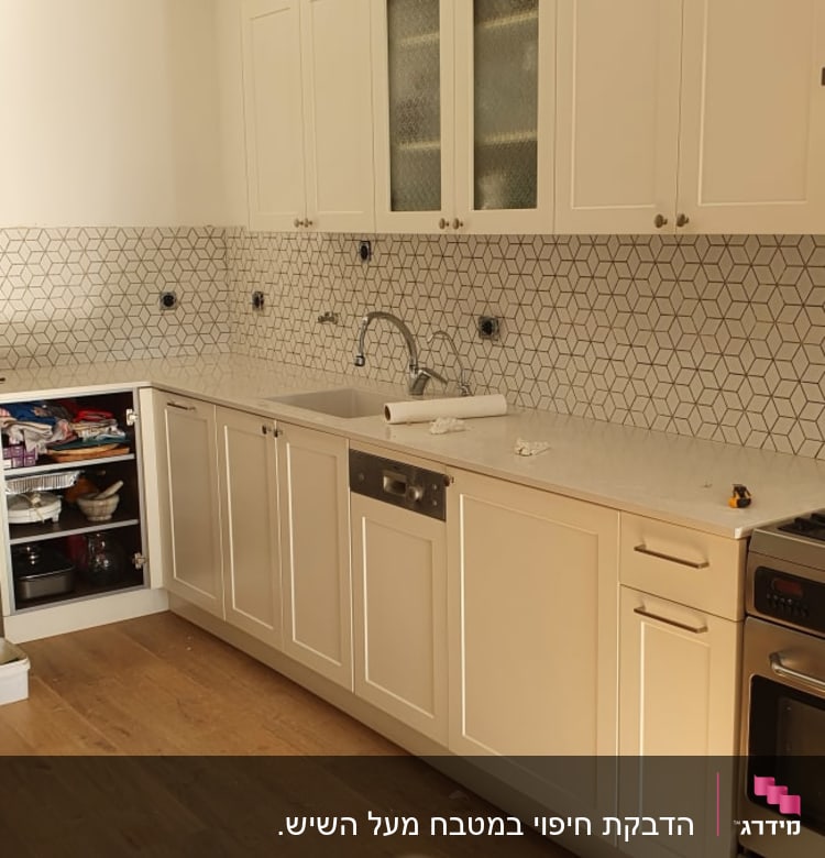 מטבח בשיפוץ עם אריחים חדשים וכלים על השיש